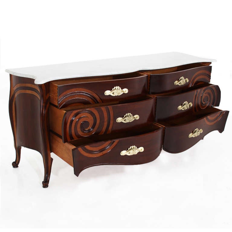 A lovely sculptural credenza in solid mahogany with two-tone stained doors and sides that highlight the spiral pattern carved into the wood. The top is white Carrara marble with a beveled edge, and the pulls are original solid brass with some light