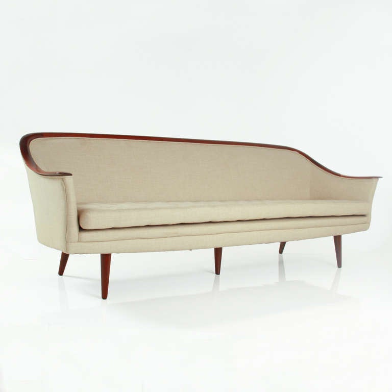 An elegant 8 foot sofa with sculptural back and arms in walnut wit tufted cream linen upholstery and turned walnut feet. 

Additional measurements:
Seat Depth: 20