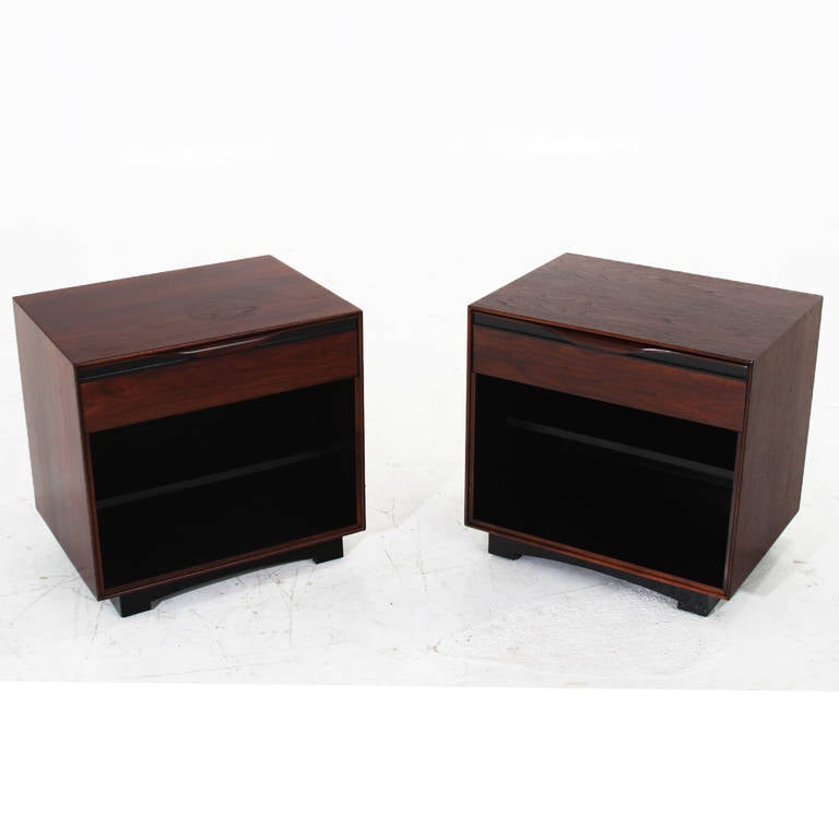 A pair of lovely walnut nightstands with black trim and black bases by Glenn of California with carved solid walnut drawer pulls.

 