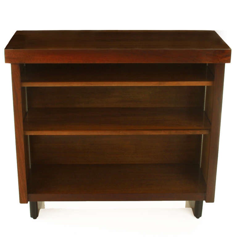 A low walnut open cabinet or book case with black sled legs and two adjustable shelves.