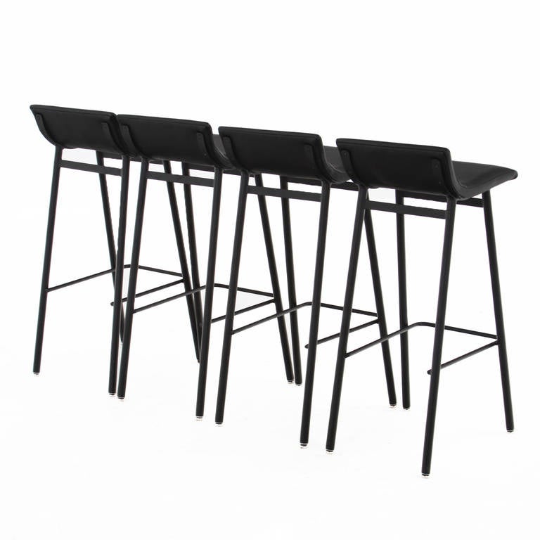 Custom order steel bar stools with curved leather seats by Thomas Hayes Studio. These stools are sturdy and comfortable and are available with tufted seat or with a single seam as shown in these photos. The legs are capped with adjustable chrome