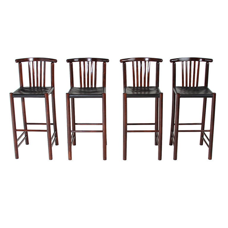 A set of four stunning vintage Danish bar stools in wood with a satin lacquer finish. The seats are upholstered in a thick black leather that is original. 

Seat depth 14