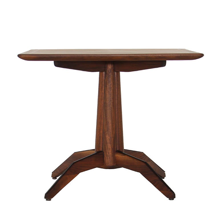 An elegant center table by Monteverdi-Young in Walnut. The top has an ebonized inlay towards the edge of the top. The base has four legs that splay out and are lined with an ebonized raised lining.

 