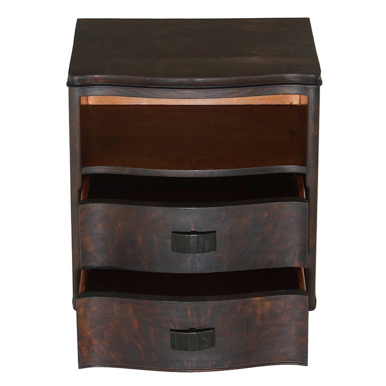A simple designed side table by John Stuart in Walnut with a charcoal oil finish & chocolate brown finish on the open shelf. The table has two drawers with ribbed metal handles and an open shelf above the drawers. The four feet are rounded conical