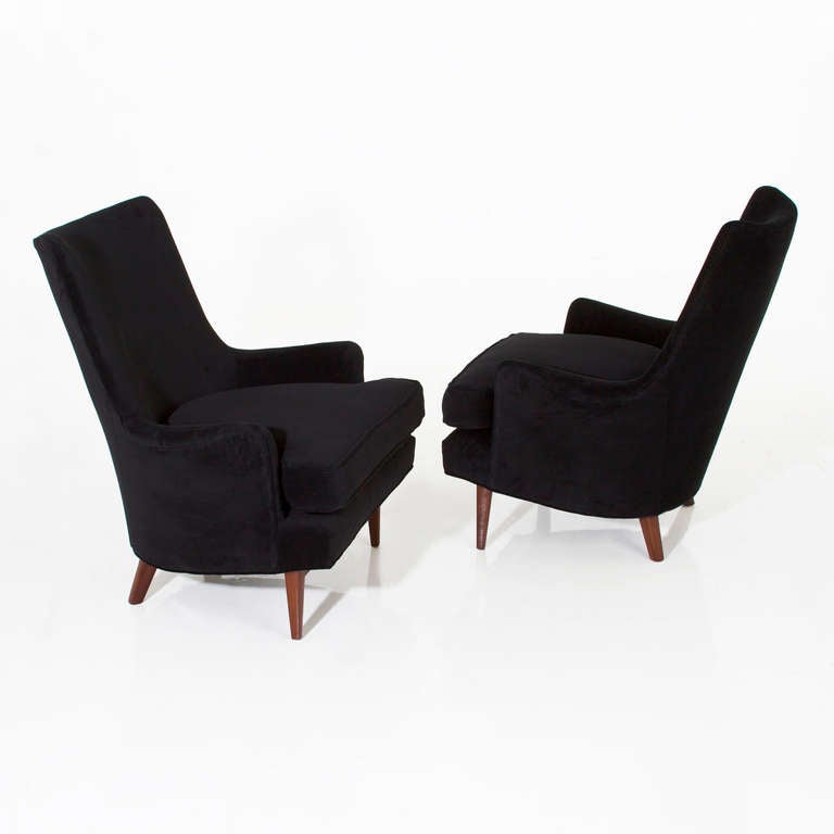 Pair of comfortable arm chairs with tapered curved backs upholstered in a lush black velvet. The tapered legs are solid mahogany. 

 