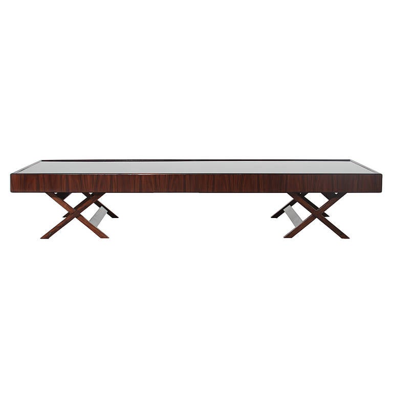 A beautiful Brazilian low coffee table in Rosewood with a reverse painted glass top. The base is X shaped on either ends with a slanted beam attaching each end of the X shaped base. 

Many pieces are stored in our warehouse, so please click on