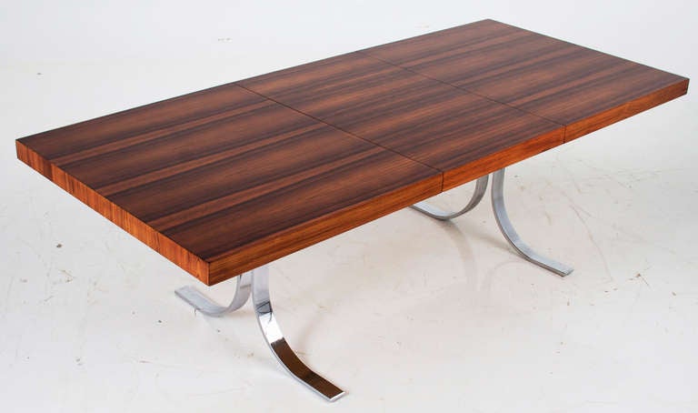 A vintage dining table with beautifully grained rosewood top and splayed leg chrome-plated solid steel base. Table comes with one removable leaf. Some chrome is pitted and has minor loss that is not distracted from the base. 

Length without