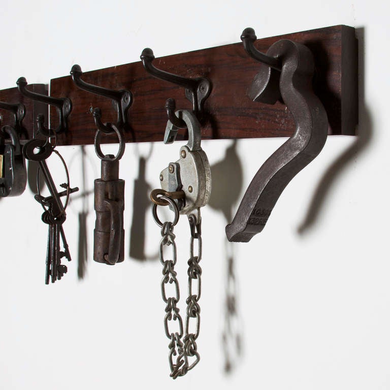 A collection of vintage iron hardware displayed on a solid Rosewood panel. Includes a set of keys on a round keychain, a lock, and an amazing hand cuff. Sold as a set. Another one is available with all locks. 

Objects hanging