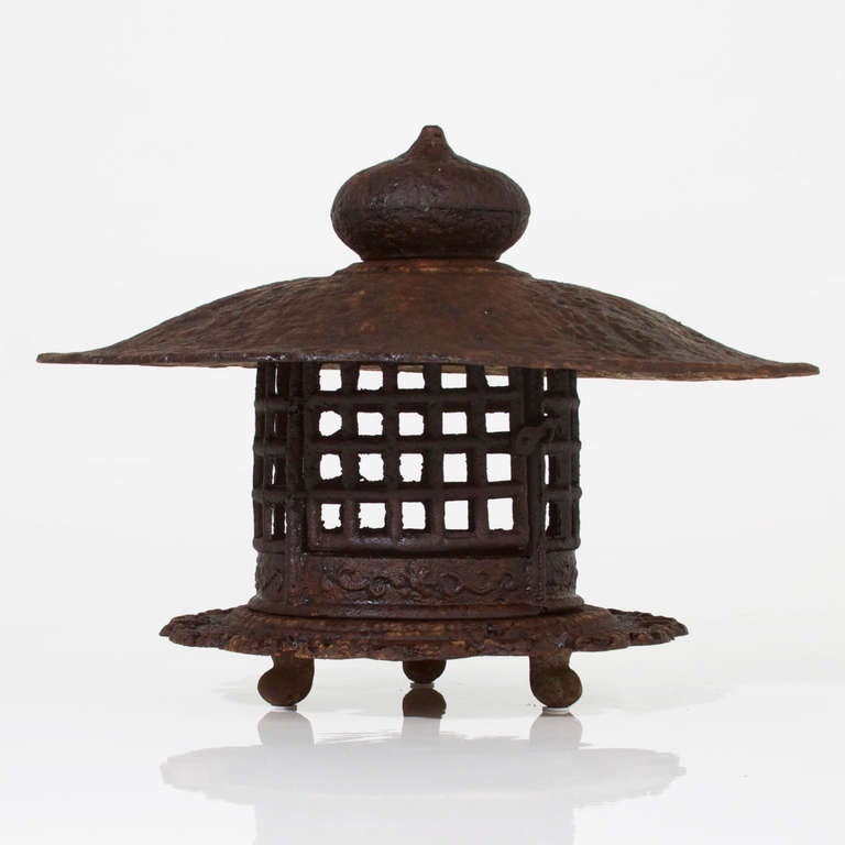 A beautifully aged solid cast iron Chinese Pagoda style lantern. The top is removable and reveals space to hold candles. The large top also makes it appropriate for outdoor use and protects the light from weather. 