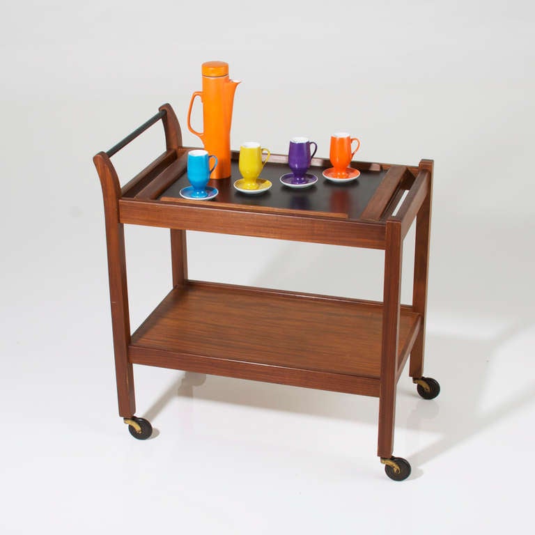 A walnut bar cart by Glenn of California on rollers with walnut shelf and inset removable tray on top in walnut and black melamine.

  