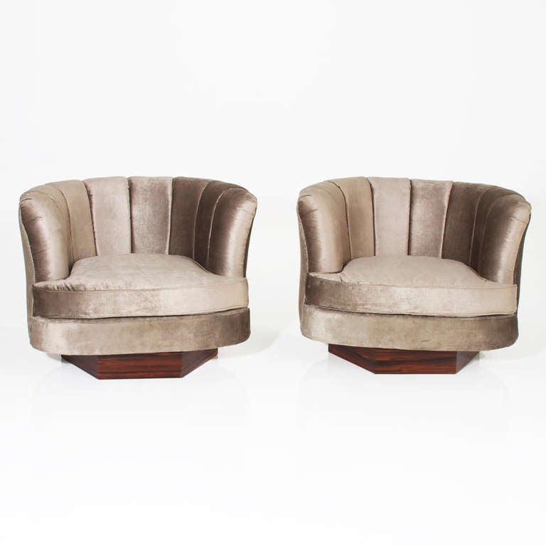 A pair of comfortable swivel chairs with rounded scalloped backs upholstered in a green/gray silk velvet on hexagon shaped Rosewood bases Milo Baughman Attribution. The arms flare out when viewed from the front.

Many pieces are stored in our