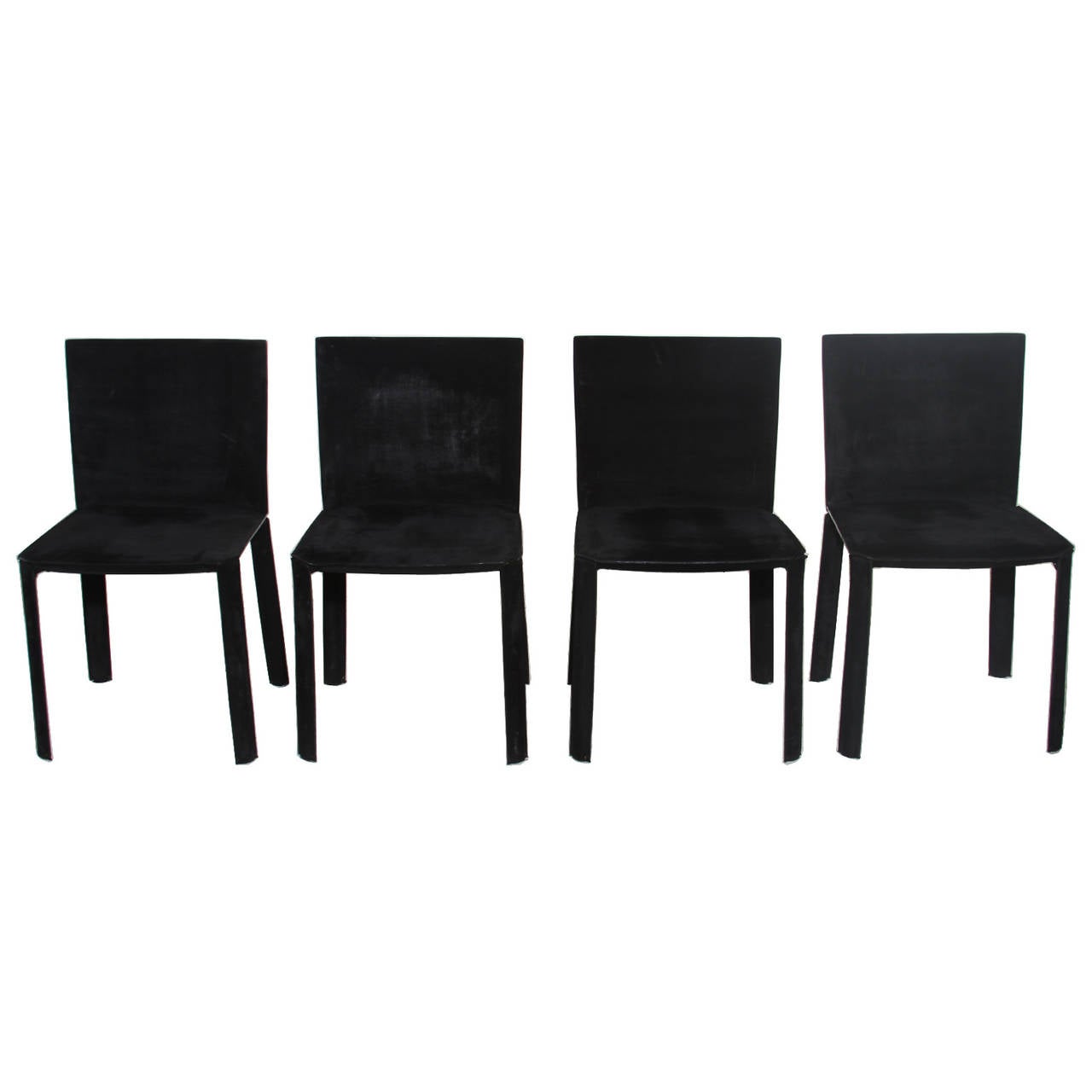 A beautiful set of four dining chairs from Brazil. The chairs are very simply designed and have an elegant look. The chairs are steel frames wrapped in a belt thickness black leather with a suede like appearance and feel. Leather has been burnished