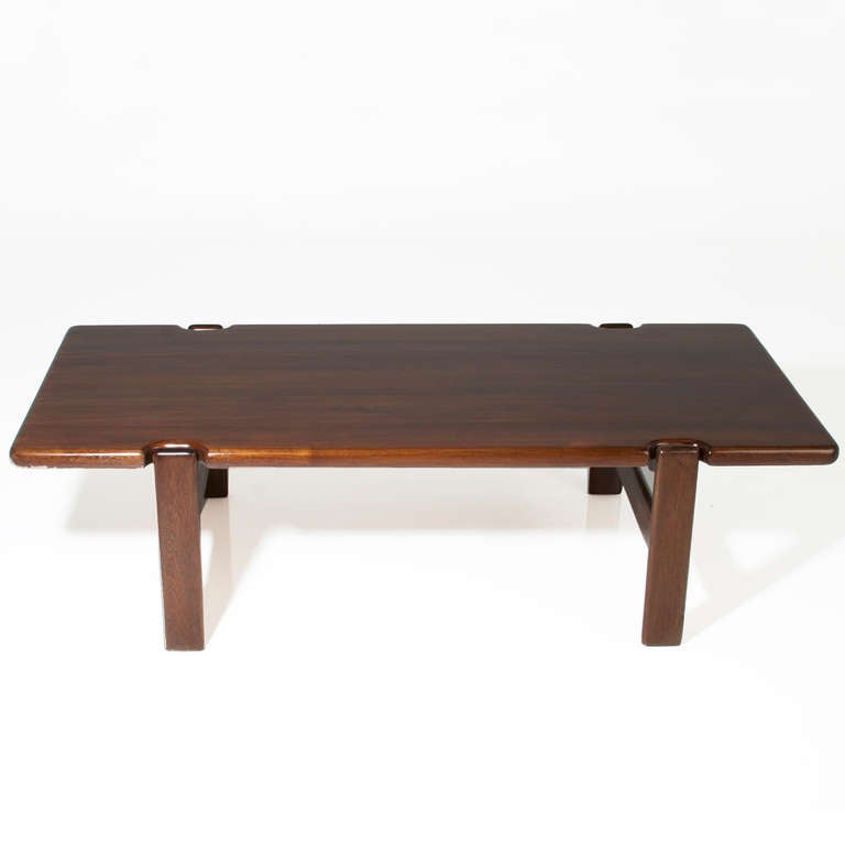 A vintage staved solid teak coffee table from Brazil with sculptural design and cut-out detailing at the top of the four legs. Labeled 