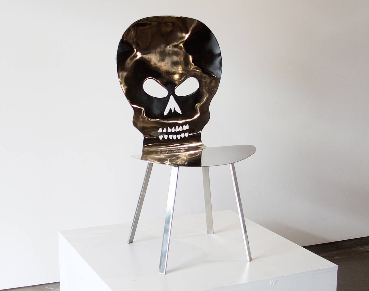 A uniquely designed chair/sculpture by Brazilian designer Alê Jordão. The chair is made of stainless steel. The seat back has a skulls face with and has been hammered. The concept of this piece is 