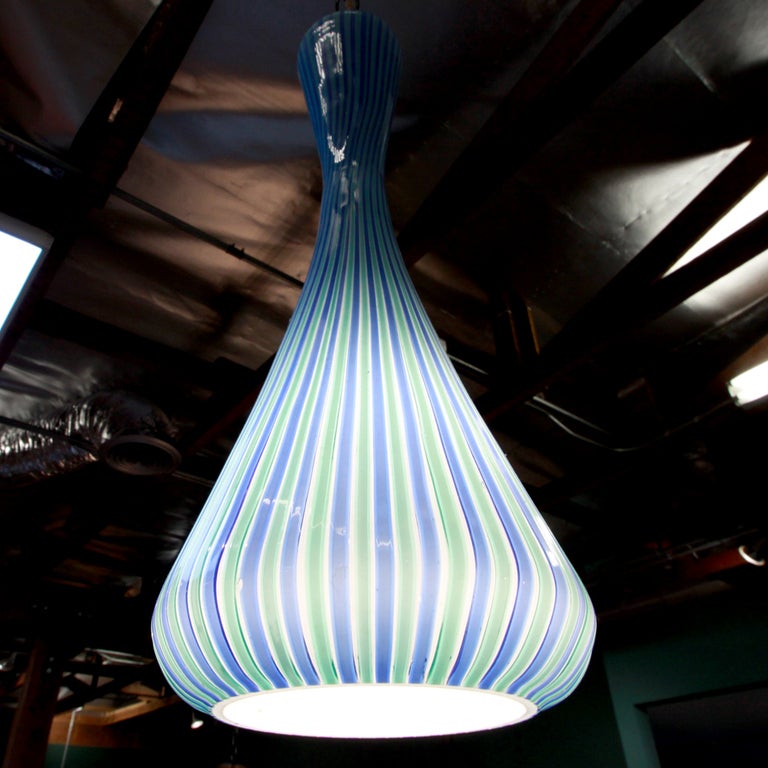 Striped green and blue white glass Venini pendant in an hourglass shape that is more bulbous and transparent on the bottom, when turned on.

Many pieces are stored in our warehouse, so please click on CONTACT DEALER under our logo below to find