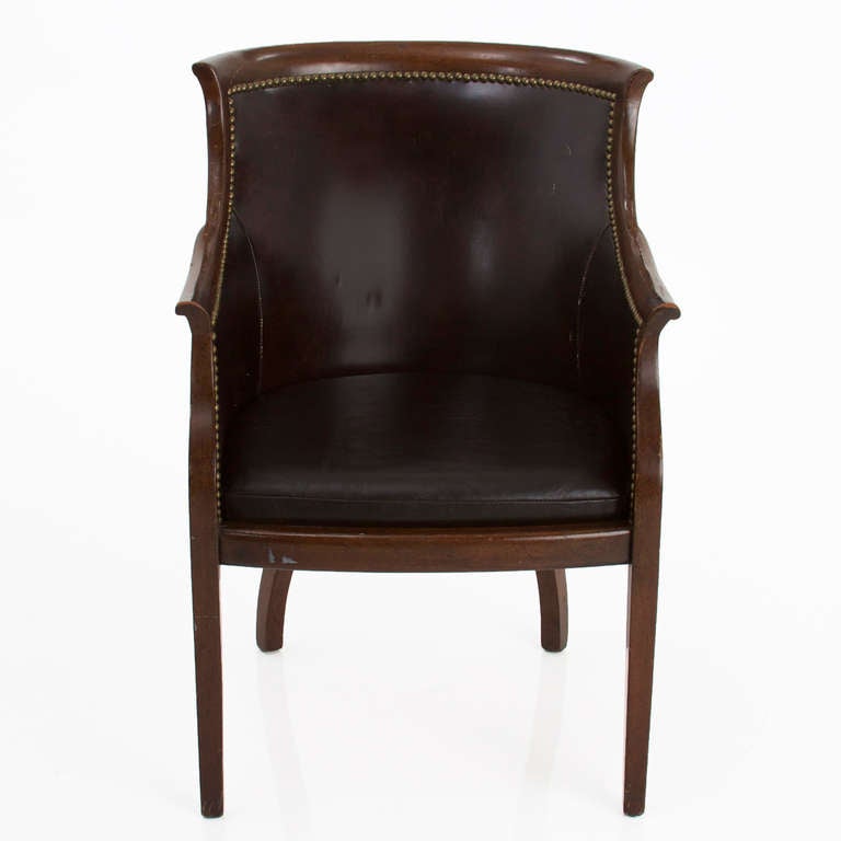 A vintage armchair with solid mahogany frame, distressed dark brown leather and metal studs as accents. Seat has been reupholstered in a 