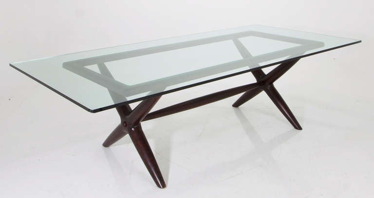 Brazilian sculptural dining table with an X-shaped base and a glass top. The sculptural base supports are 4 inches thick at thickest. This base has a glass top that measures 97" x 48" but could accommodate a larger top. Wood is most likely