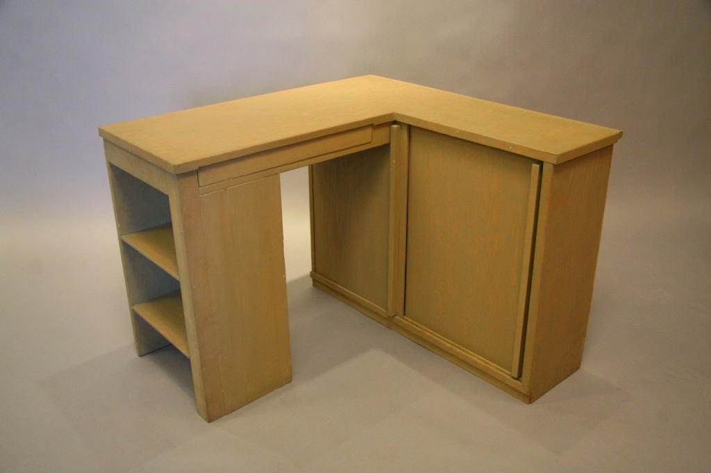 A small painted wood desk with additional storage that fits snuggly into a corner designed by Rudolph Schindler. Enclosed side of the desk measures 11 1/2