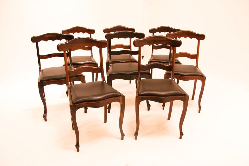 A set of eight vintage Brazilian dining chairs with sculptural frames, scalloped edge backs and black leather seats from Brazil. These chairs were crafted in the Portuguese tradition in the Sao Christavo neighborhood of Rio De Janeiro. Seat depth: