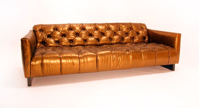 Long tufted gold leather sofa with rectangular wood bases. Seat depth measures 25