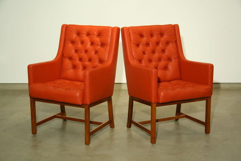 A pair of high tufted leather and teak arm chairs