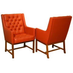 A pair of high tufted leather and teak arm chairs