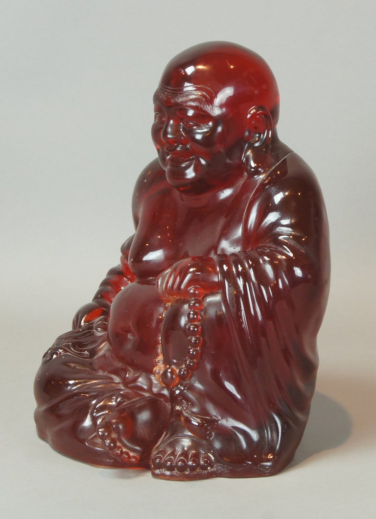 A large cast resin (cherry amber) figure of a seated buddha dating from the 1940's