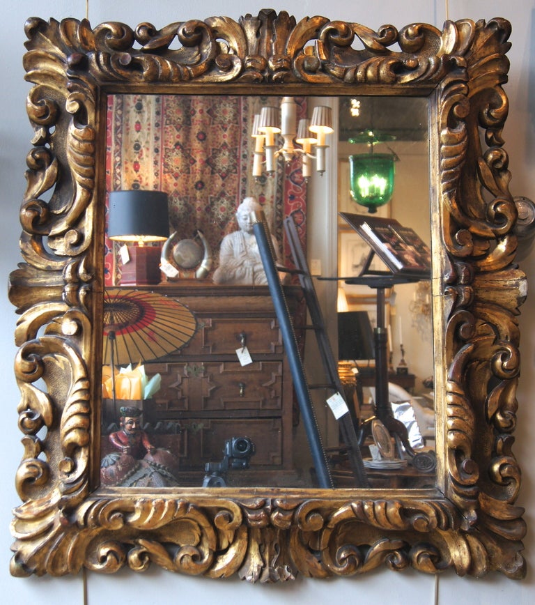 A large elaborately carved Italian giltwood mirror dating from the second half of the 18th century retaining old, possibly original, glass.