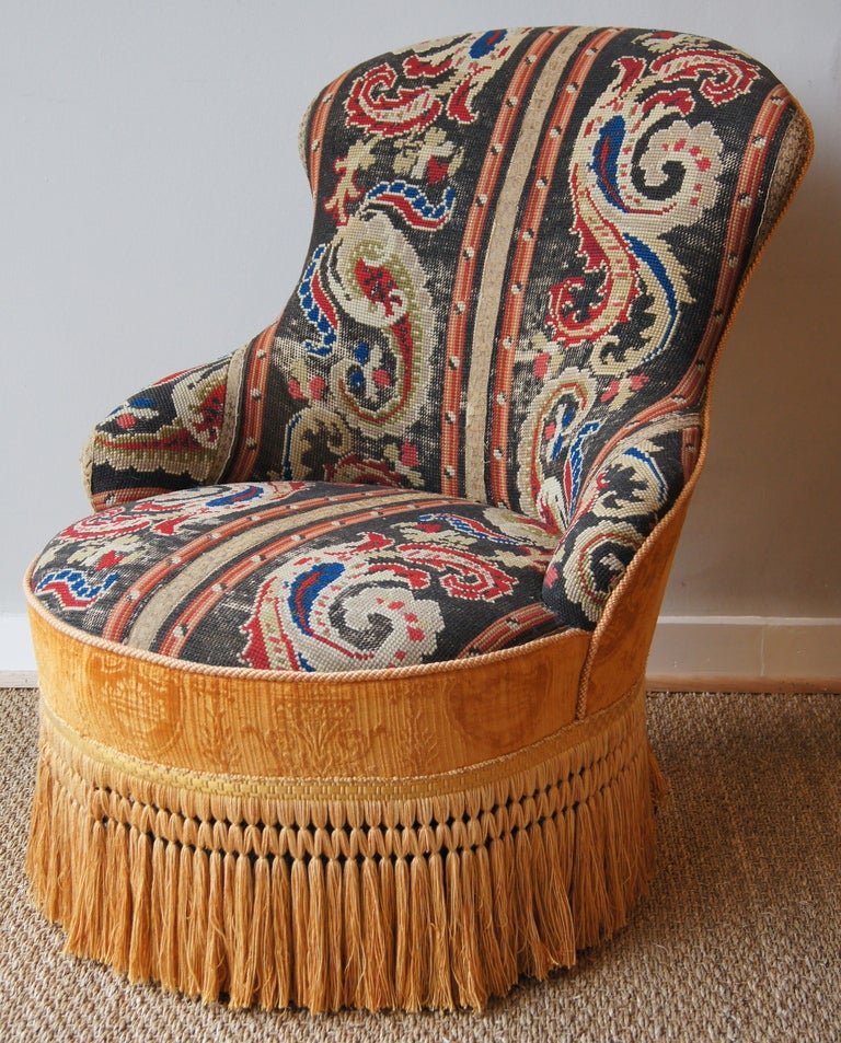 A charming early 20th century English needlepoint upholstered slipper chair accented with original velvet back and bullion fringe.