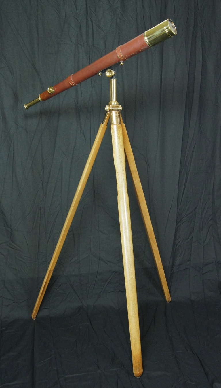 A large working brass and leather telescope on large wood tripod base manufactured by Dollond, London, England. The brass and wood base is by AG Thornton, Manchester.