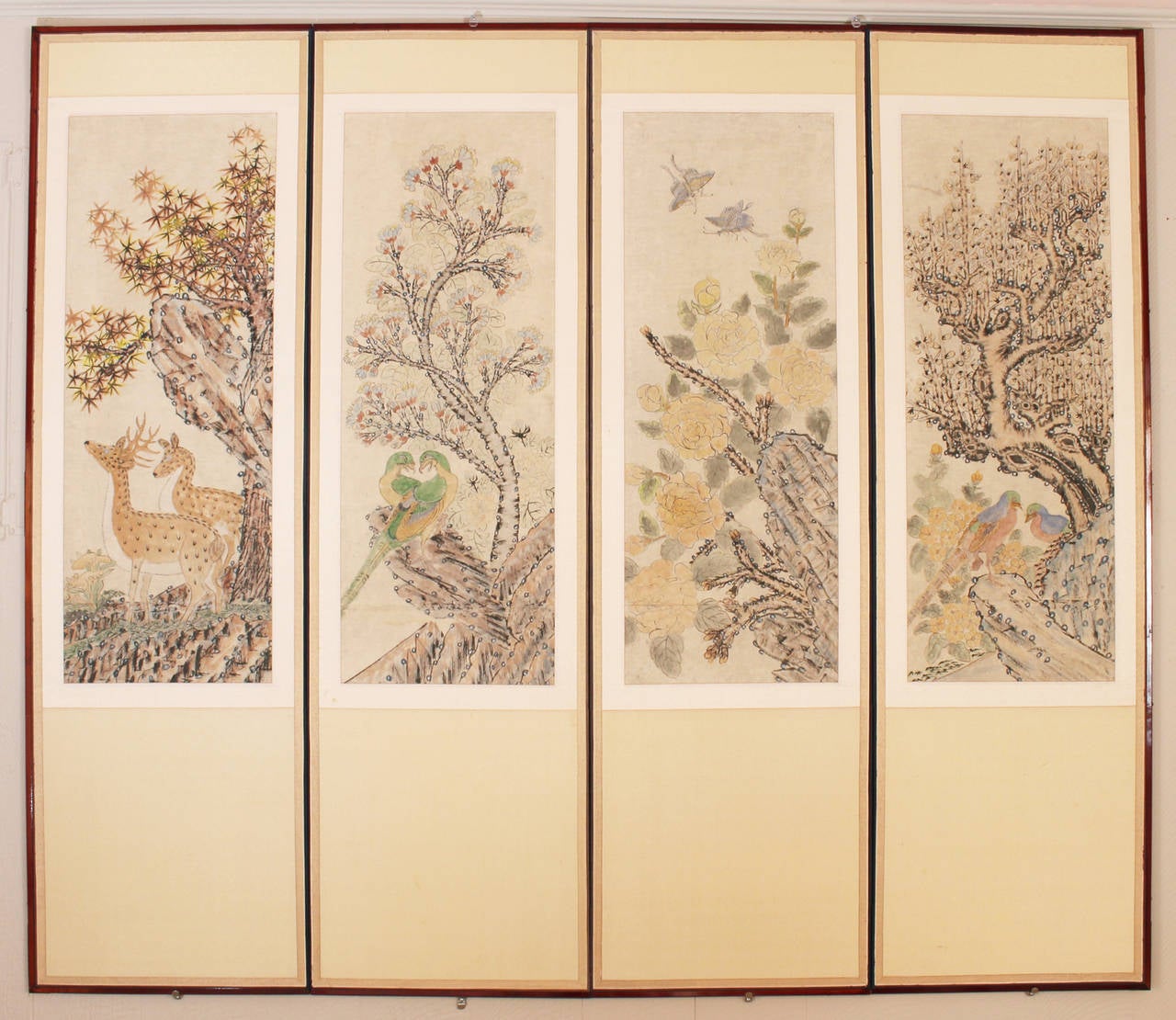 A four-panel folding screen inset with hand-painted scenes of birds and animals in a woodland setting surrounded by woven silk matting set in dark polished wood frame with brass fittings.