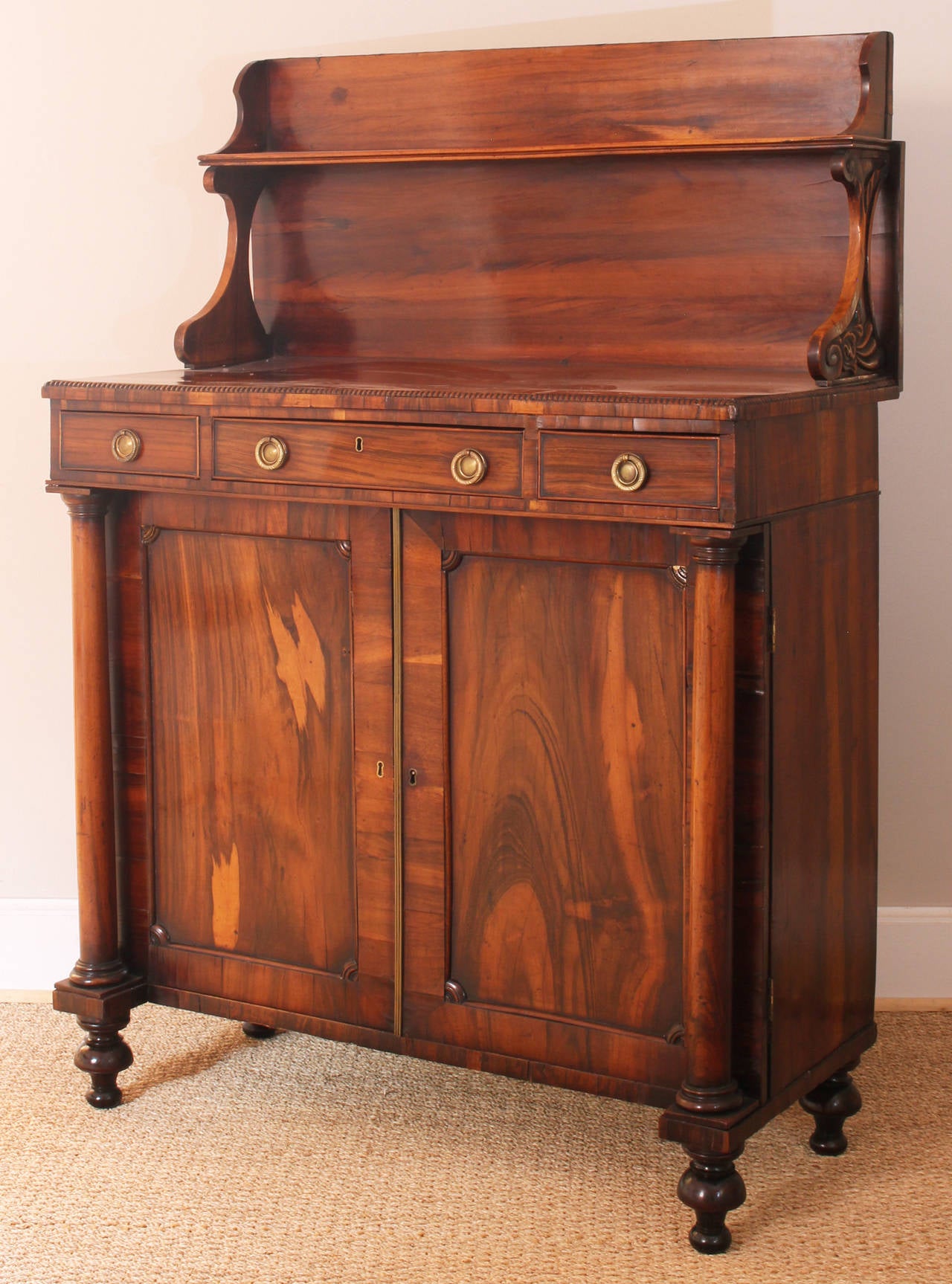 A very handsome chiffonier of beautifully figured rosewood having three drawers, the center opening to a fitted writing surface above double cabinet doors.