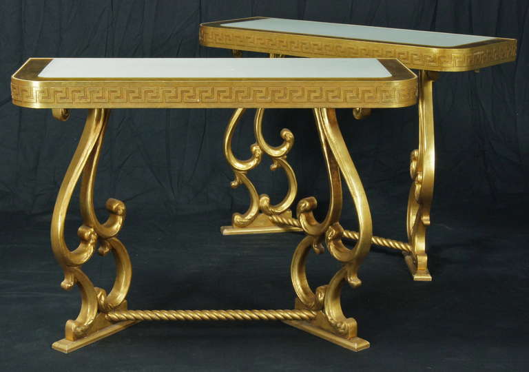 A pair of Neoclassical style giltwood console tables dating from the 1980's with inset white glass tops and Greek key decoration.