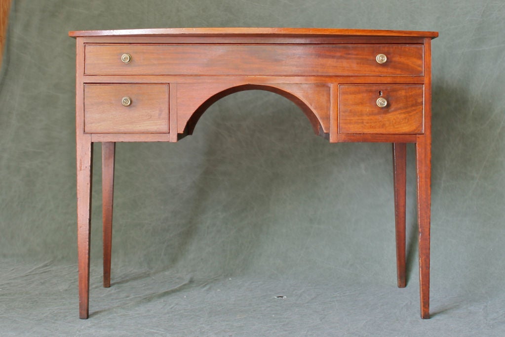 A rare English Hepplewhite mahogany brandy board featuring a single board demilune top, one over two cog beaded and dovetailed drawers with delicately tapered legs