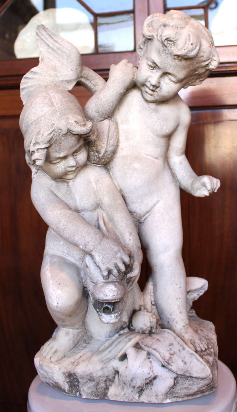 A charming late-19th Century Italian carved marble fountain depicting cherubs frolicking with a dolphin. The fountain spouts from the dolphin's mouth.