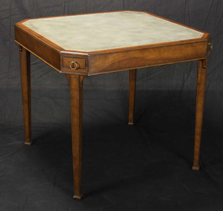 An elegant mid-20th C. mahogany games/card table with inset pale blue leather top with gilt embossed decoration. Each of the four chamfered corners house a drawer for chips and playing pieces.