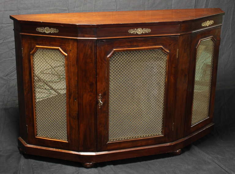 An elegant English rosewood three door cabinet credenza with mirror backed grillwork and applied gilt bronze acanthus leaf mounts resting on bun feet.