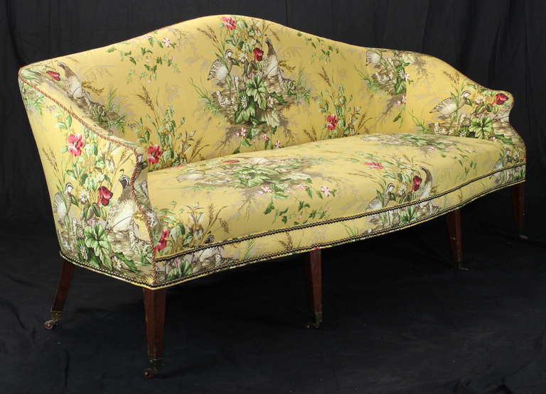 An elegant and comfortable early 19th century sofa with gently curving back and seat covered in a rich yellow cotton chintz accented with brass tacks.