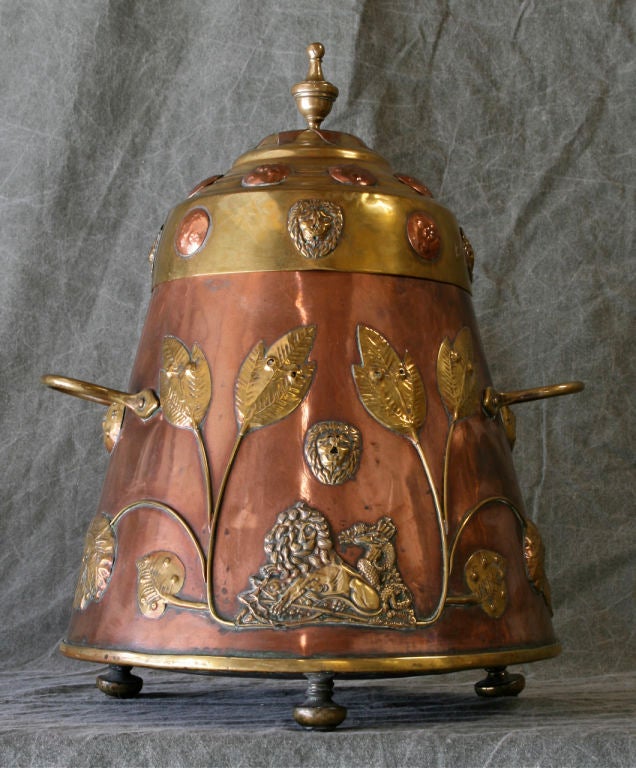 An early Dutch copper and brass coal scuttle with applied repousse decoration depicting a recumbent lion intertwined with a crowned serpent, the entirety being supported by three bun feet.