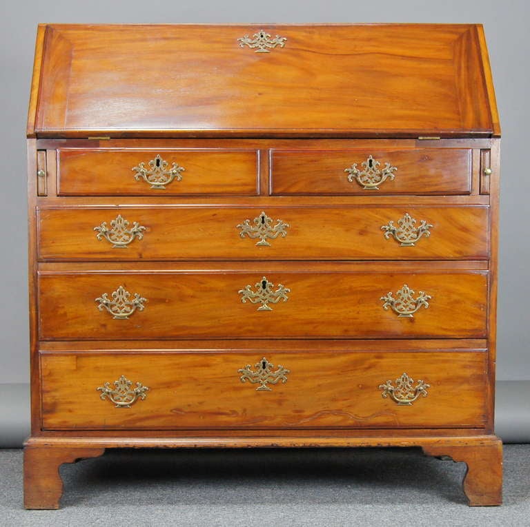 A lovely late 18th century American slant front desk in mellow sun-faded mahogany with fitted interior above five drawers with bracket feet and replaced brasses.