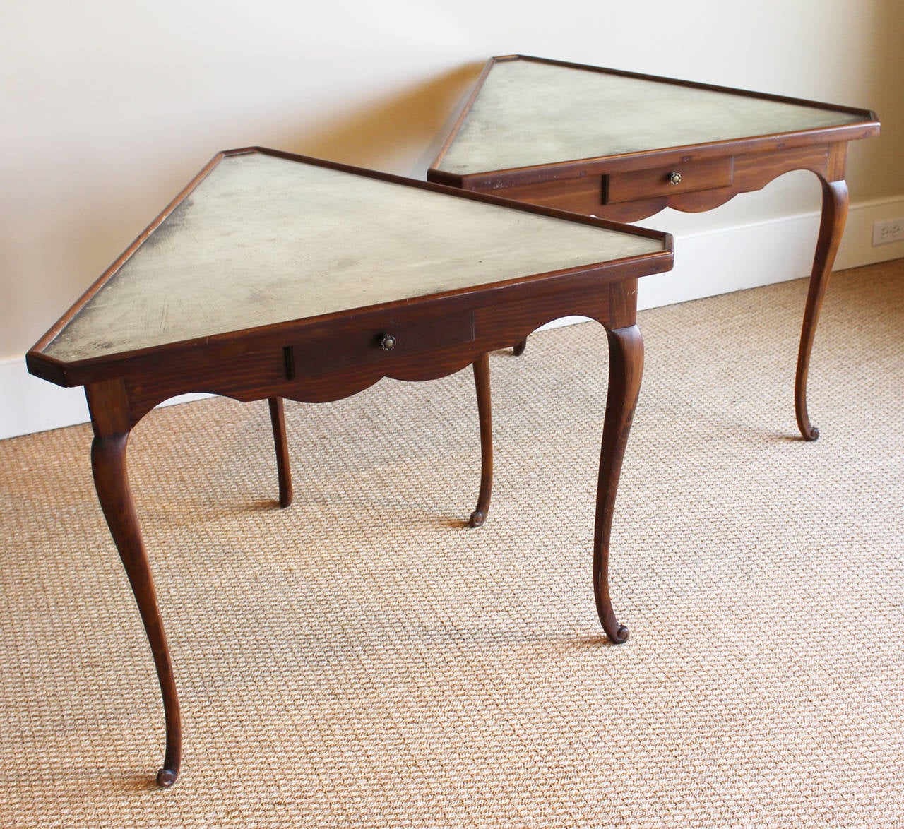 An unusual pair of 1940s Italian triangular-shaped tables with elegantly carved legs and skirts each fitted with a drawer and antiqued mirror tops.