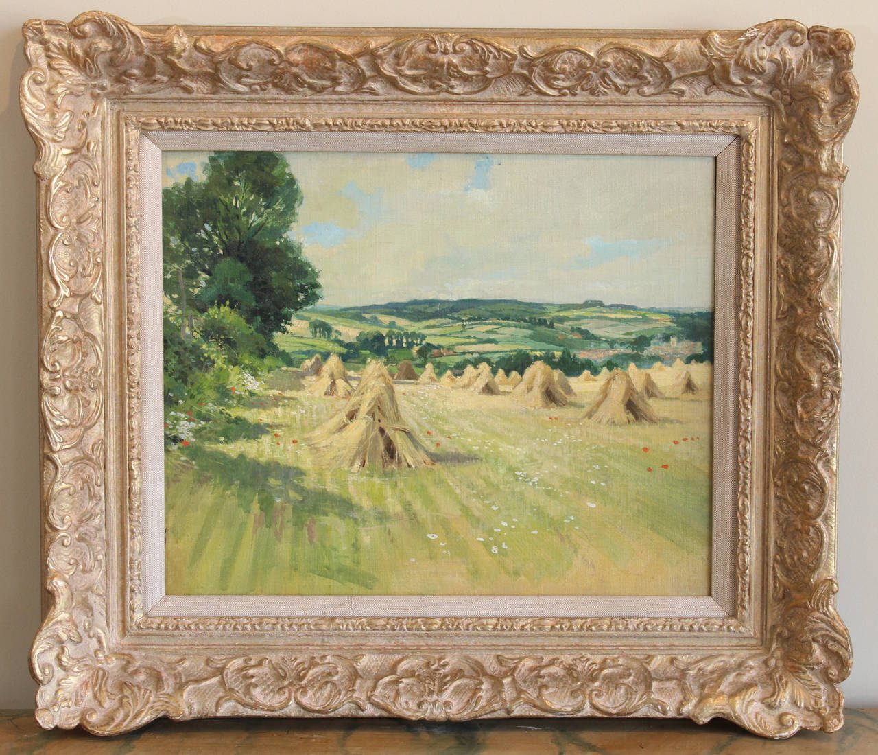 A charming early 20th century oil on canvas painting of haystacks in a field by Stanley Charles Rowles in original carved giltwood frame.