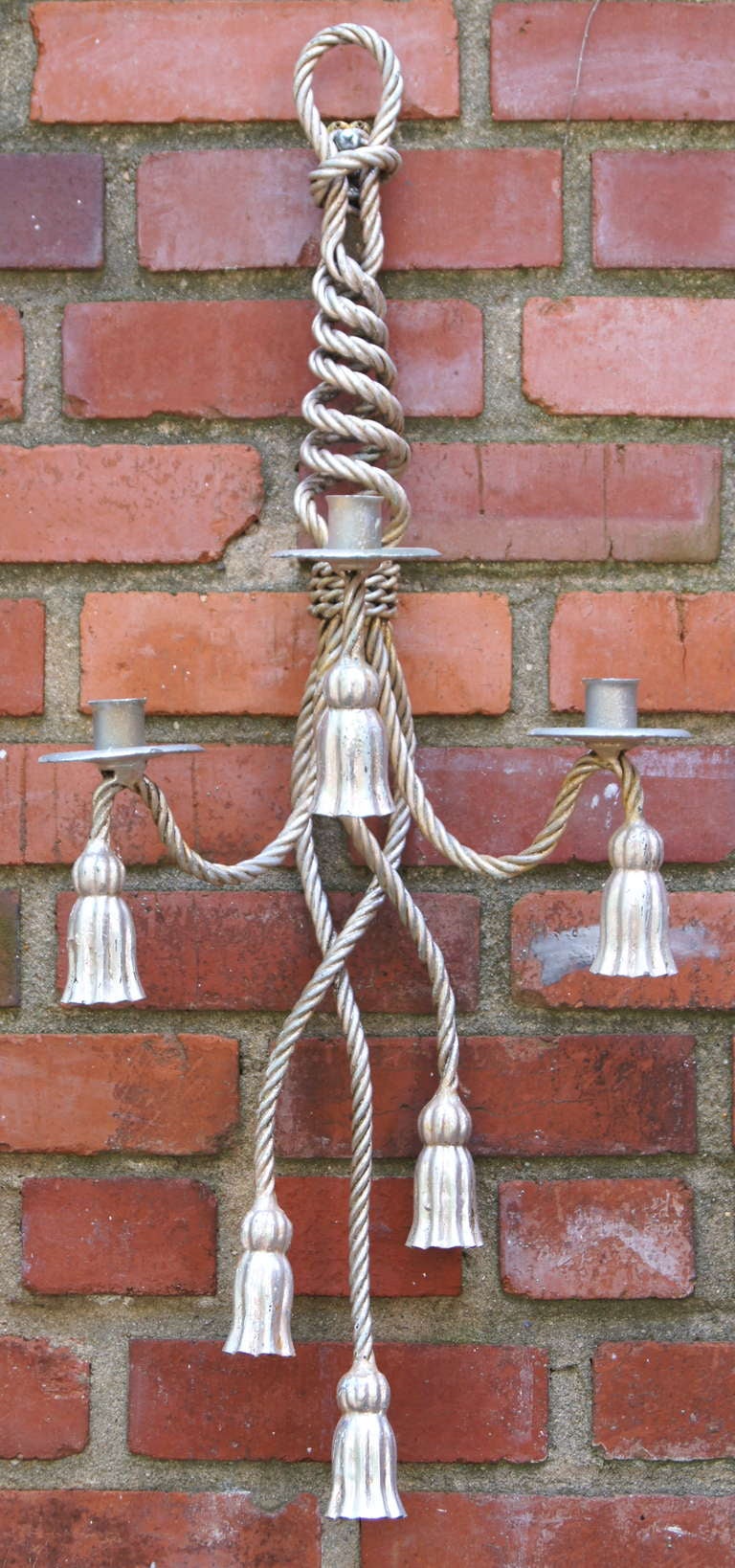 A pair of circa 1950s silver leafed three-light metal sconces in the fashion of tied and braided rope with tassels.