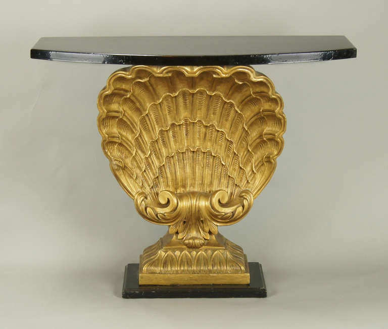 Stunning Grosfeld House Hollywood Regency console table with gilded shell motif and ebonized top and base.