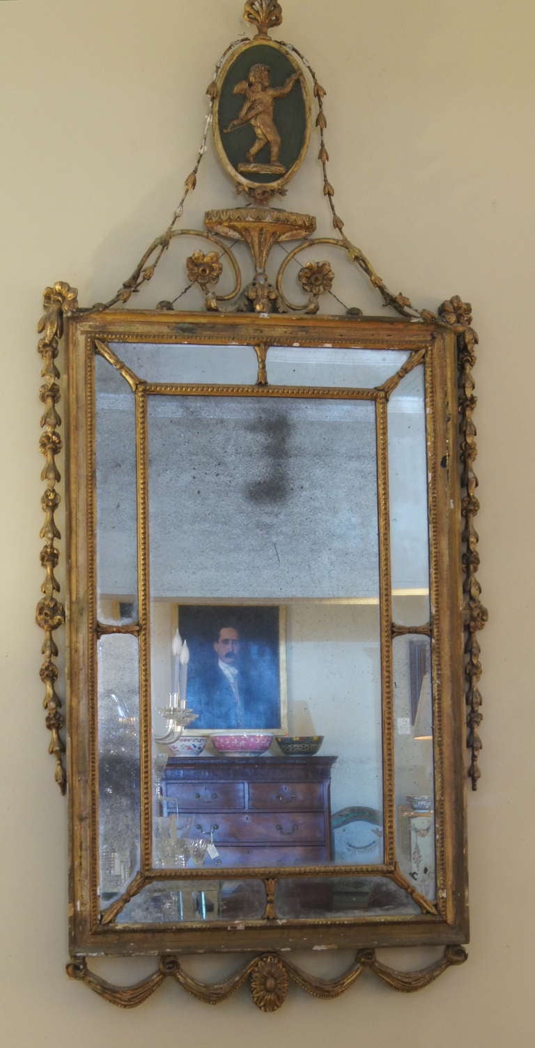A very elegant Adam style rectangular giltwood mirror with molded inner border and divided glass. An urn and cherub inset oval finial is flanked by draped bellflowers continuing down the sides of the frame.
