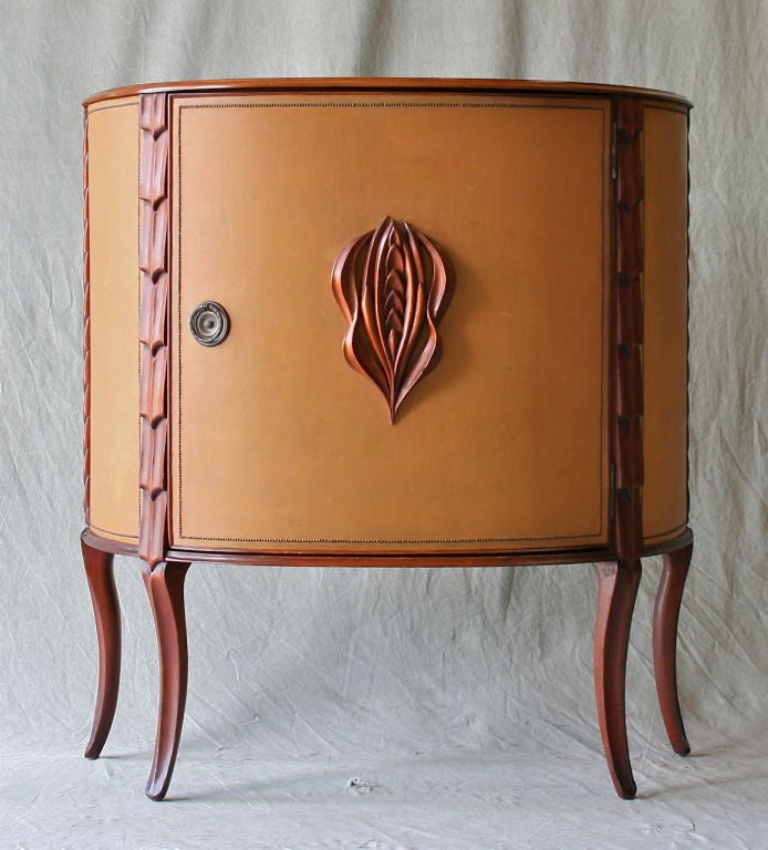 An elegant custom-made Art Deco demi-lune cabinet in carved mahogany and leather made by Stanley Saltz of Reading Pa. Saltz was a local craftsman/cabinet maker working in the area throughout the 30s and 40s.