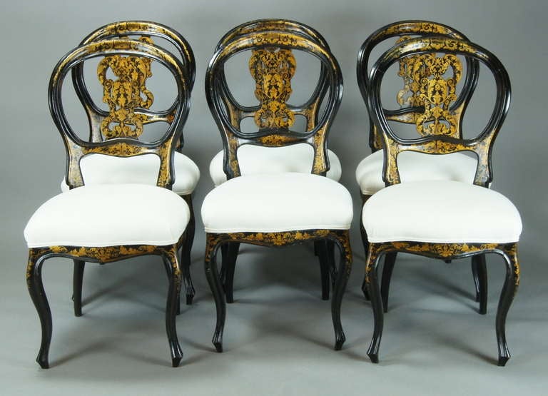 An elegant set of six mid-19th century. English black lacquer and gilt decorated balloon-back dining chairs with graceful cabriole legs recently upholstered in a white linen fabric.