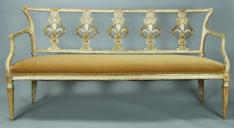 A very intricately carved late 18th C. parcel gilt and paint decorated Italian Neoclassical bench newly upholstered in light brown velvet.