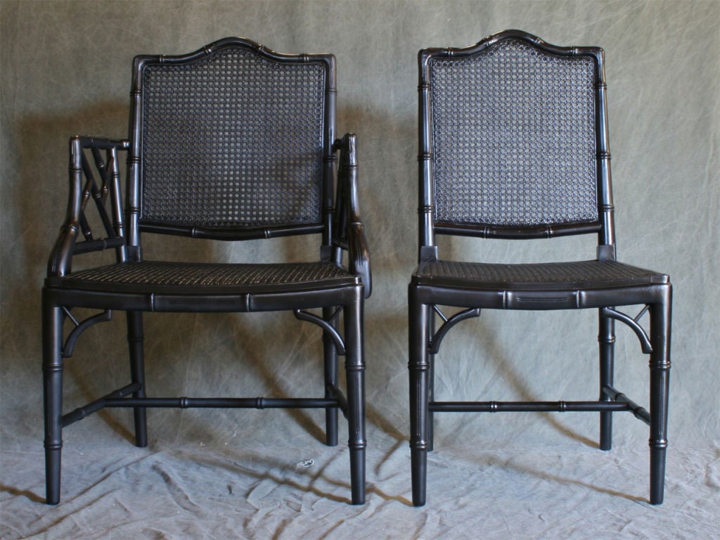 A set of six faux bamboo Chinese Chippendale dining chairs comprised of two armchairs and four sidechairs.  The carved wood frames are painted a mellow black with the faintest suggestion of brown. The cane seats are in excellent condition and have