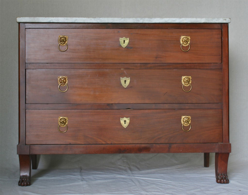 A substantial South German commode made of cherrywood accented with shield shaped escutcheons and lion head pulls. The mellow grey-white marble top is original to the piece.